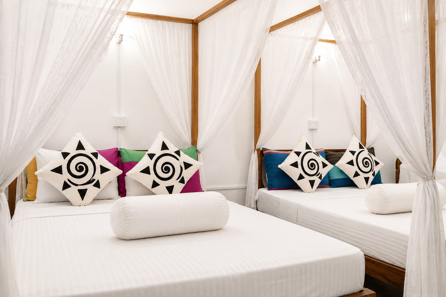 Deluxe Family Room: two four-poster beds under white mosquito netting, with teak frames and hand-printed cushions.